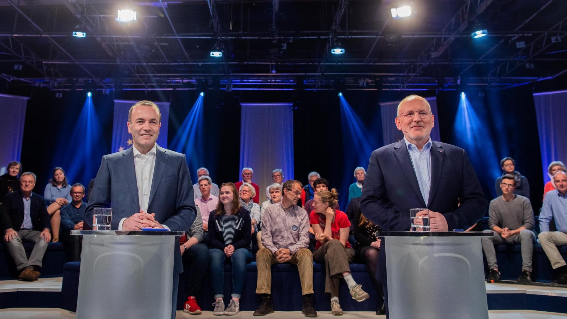 Das Bild zeigt Manfred Weber und Frans Timmermans, Sie stehen während einer Fernsehdebatte hinter Pulten. Das Bild zeigt Manfred Weber und Frans Timmermans, Sie stehen während einer Fernsehdebatte hinter Pulten.