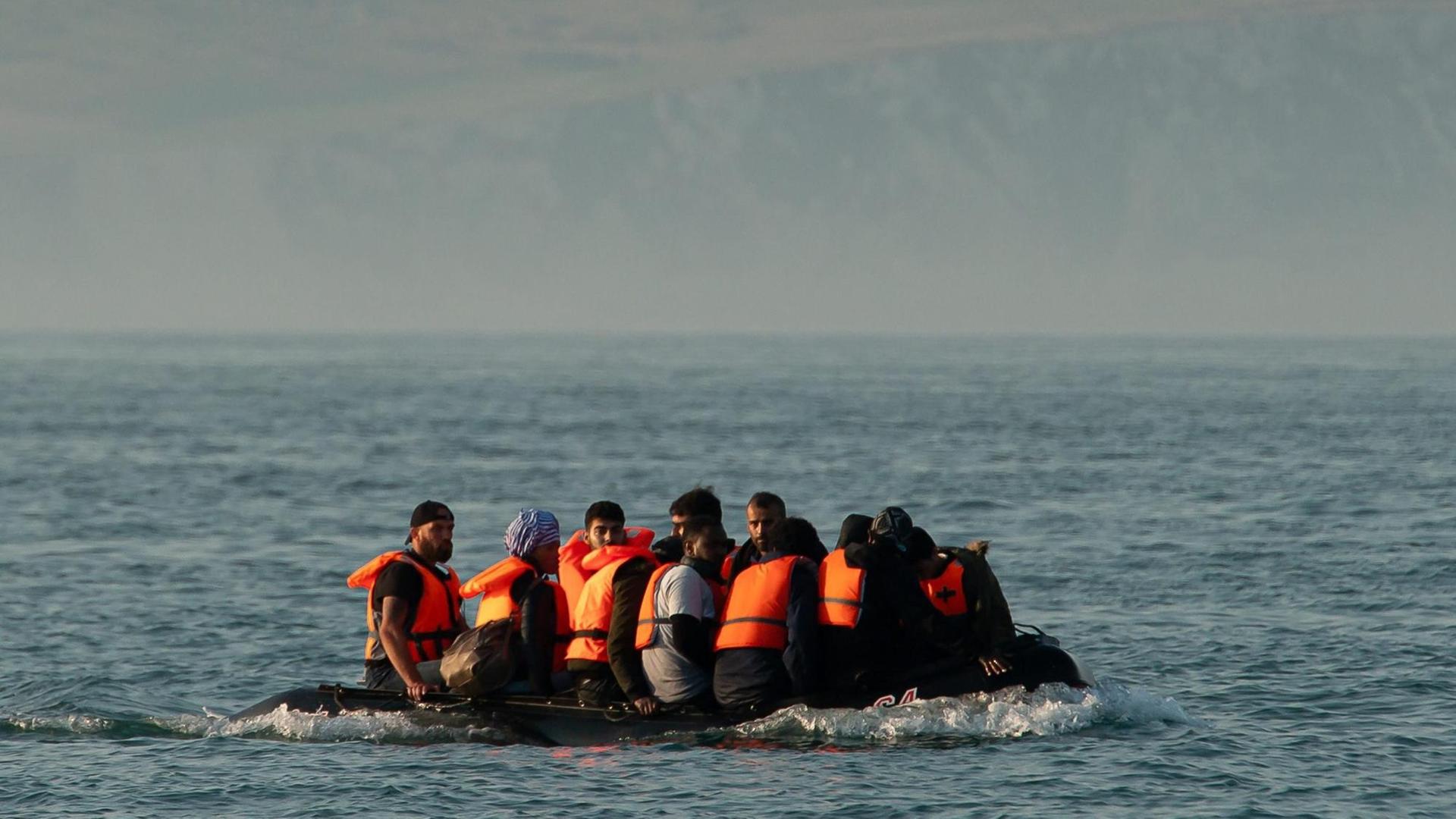 Flüchtende dicht gedrängt in einem Schlauchboot auf dem Ärmelkanal bei dem Versuch, Großbritannien zu erreichen. Im Hintergrund die felsige Küste von Cap Blanc-Nez, südlich von Calais. Flüchtende dicht gedrängt in einem Schlauchboot auf dem Ärmelkanal bei dem Versuch, Großbritannien zu erreichen. Im Hintergrund die felsige Küste von Cap Blanc-Nez, südlich von Calais.