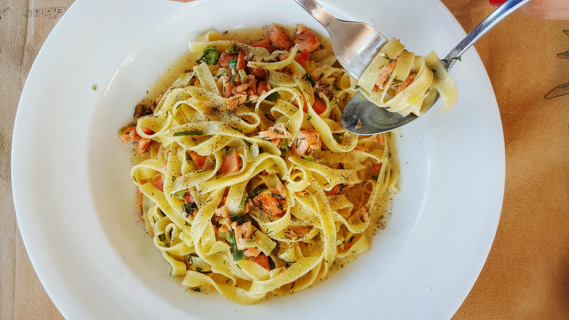 Bildunterschrift: Cucina Povera verweist auf die einfache Küche. Zu sehen: Ein Pastateller, eine Hand ist mit einem Löffel und einer Gabel zu sehen. Bildunterschrift: Cucina Povera verweist auf die einfache Küche. Zu sehen: Ein Pastateller, eine Hand ist mit einem Löffel und einer Gabel zu sehen.