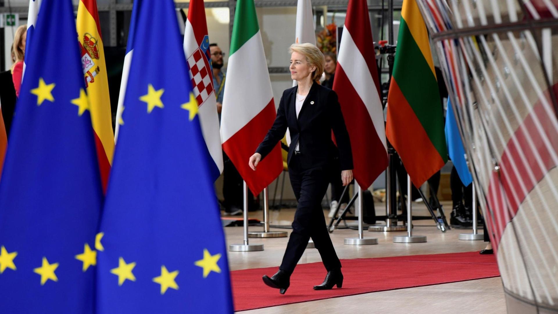 Die CDU-Politikerin Ursula von der Leyen läuft an zahlreichen Flaggen im EU-Hauptquartier in Brüssel entlang.