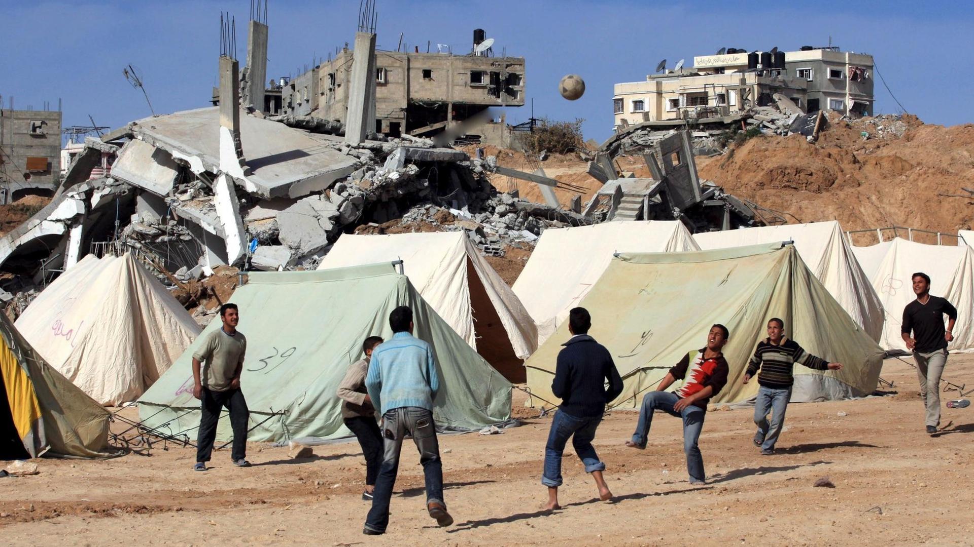 Palästinensische Jugendliche am 30. Januar 2009 beim Fußballspielen vor Zelten und zerstörten Gebäuden.