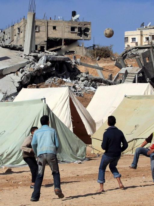 Palästinensische Jugendliche am 30. Januar 2009 beim Fußballspielen vor Zelten und zerstörten Gebäuden.