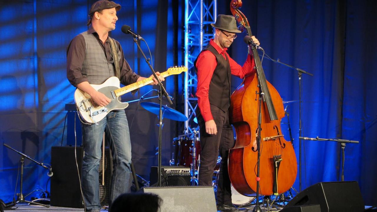 Sascha Bendiks mit Gitarre und Tobias Schwab am Kontrabaß stehen nebeneinander auf der Bühne und spielen Sascha Bendiks mit Gitarre und Tobias Schwab am Kontrabaß stehen nebeneinander auf der Bühne und spielen