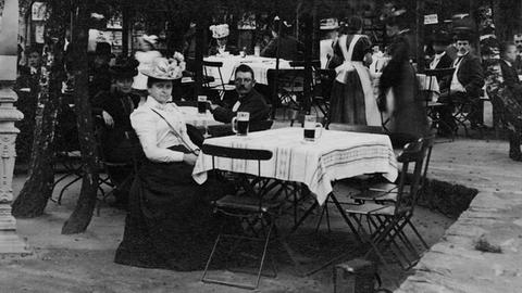 Historische Aufnahme: Gäste in einem Gartenlokal / Biergarten, um 1910.