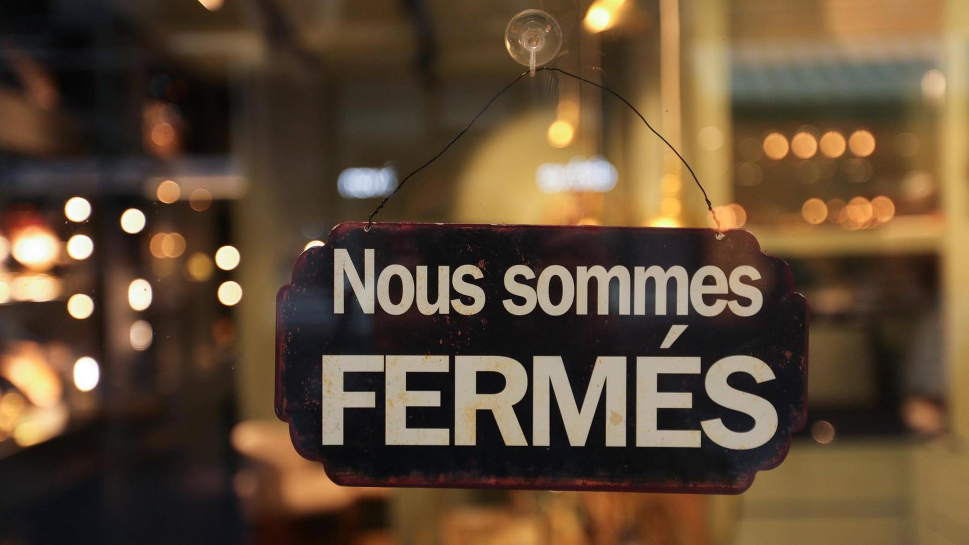 In der Tür eines Geschäftes hängt ein Schild mit der Aufschrift: "Nous sommes fermés" In der Tür eines Geschäftes hängt ein Schild mit der Aufschrift: "Nous sommes fermés"