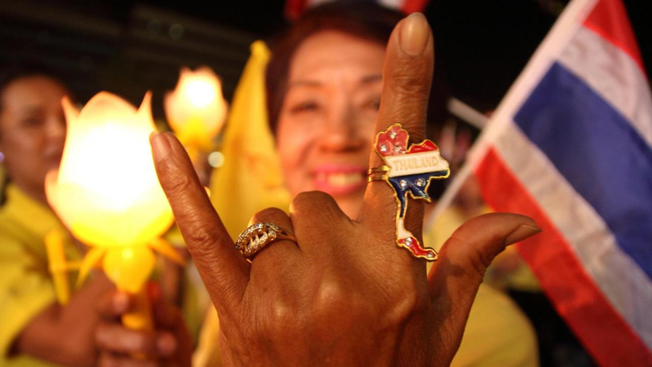 Eine erhobene Hand mit einem glitzernden Thailand Ring auf einer Demonstration.