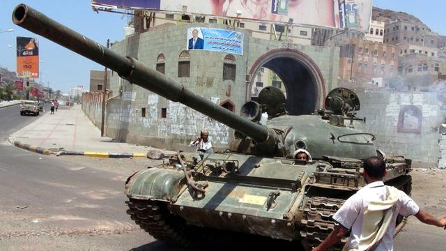 In der Hafenstadt Aden steht ein Mann vor einem Panzer der Anhänger des geflohenen Präsidenten Hadi.