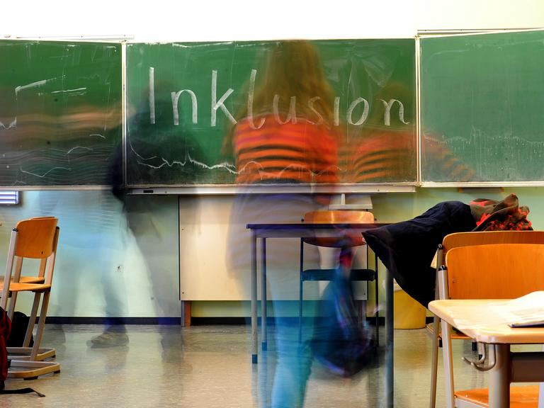 Kinder in einer Schulklasse, auf der Tafel ist das Wort Inklusion geschrieben