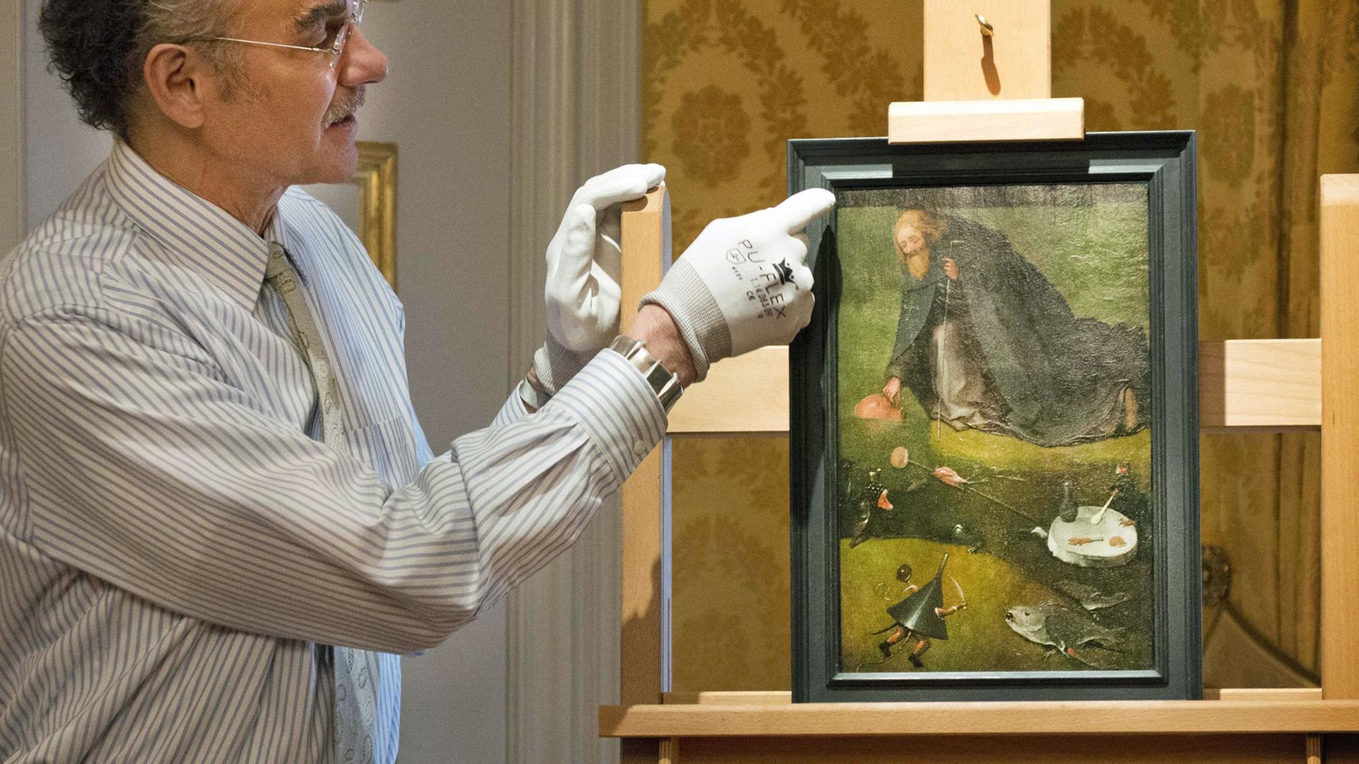 Ein Mitarbeiter präsentiert im Noordbrabants Museum in 's-Hertogenbosch das Gemälde "Die Versuchung des heiligen Antonius", das jetzt dem spätmittelalterlichen Maler Hieronymus Bosch zugeordnet wird. Ein Mitarbeiter präsentiert im Noordbrabants Museum in 's-Hertogenbosch das Gemälde "Die Versuchung des heiligen Antonius", das jetzt dem spätmittelalterlichen Maler Hieronymus Bosch zugeordnet wird.