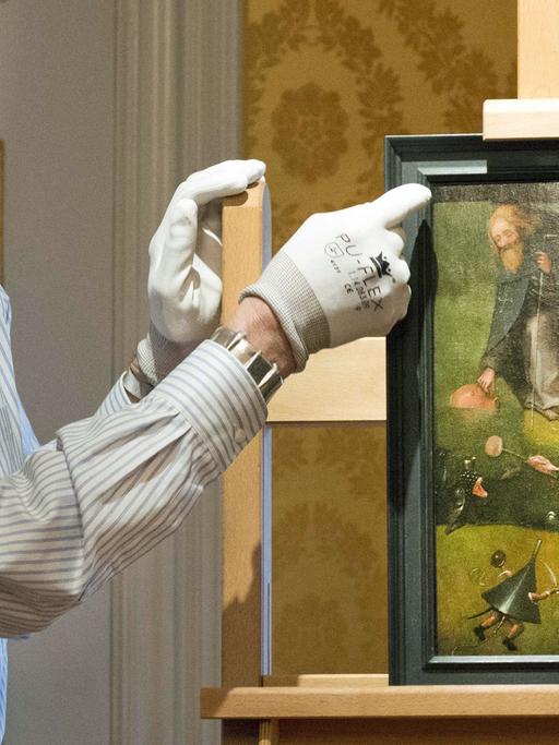 Ein Mitarbeiter präsentiert im Noordbrabants Museum in 's-Hertogenbosch das Gemälde "Die Versuchung des heiligen Antonius", das jetzt dem spätmittelalterlichen Maler Hieronymus Bosch zugeordnet wird.