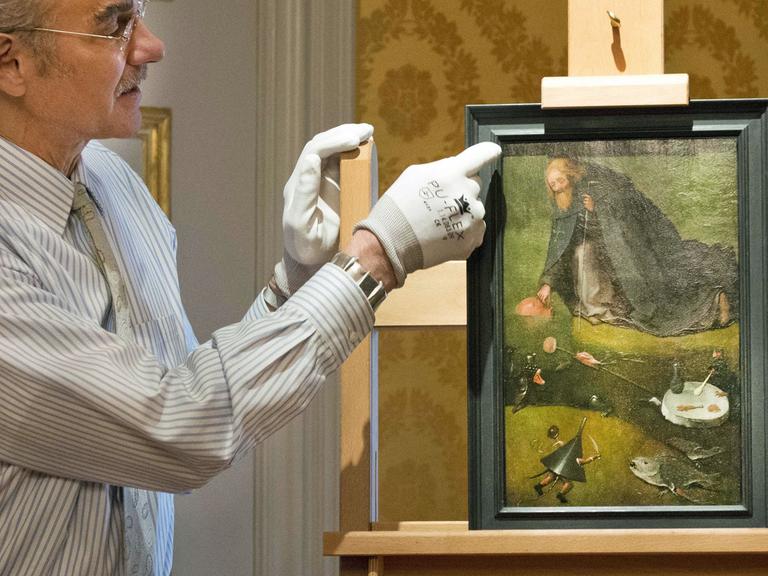 Ein Mitarbeiter präsentiert im Noordbrabants Museum in 's-Hertogenbosch das Gemälde "Die Versuchung des heiligen Antonius", das jetzt dem spätmittelalterlichen Maler Hieronymus Bosch zugeordnet wird.
