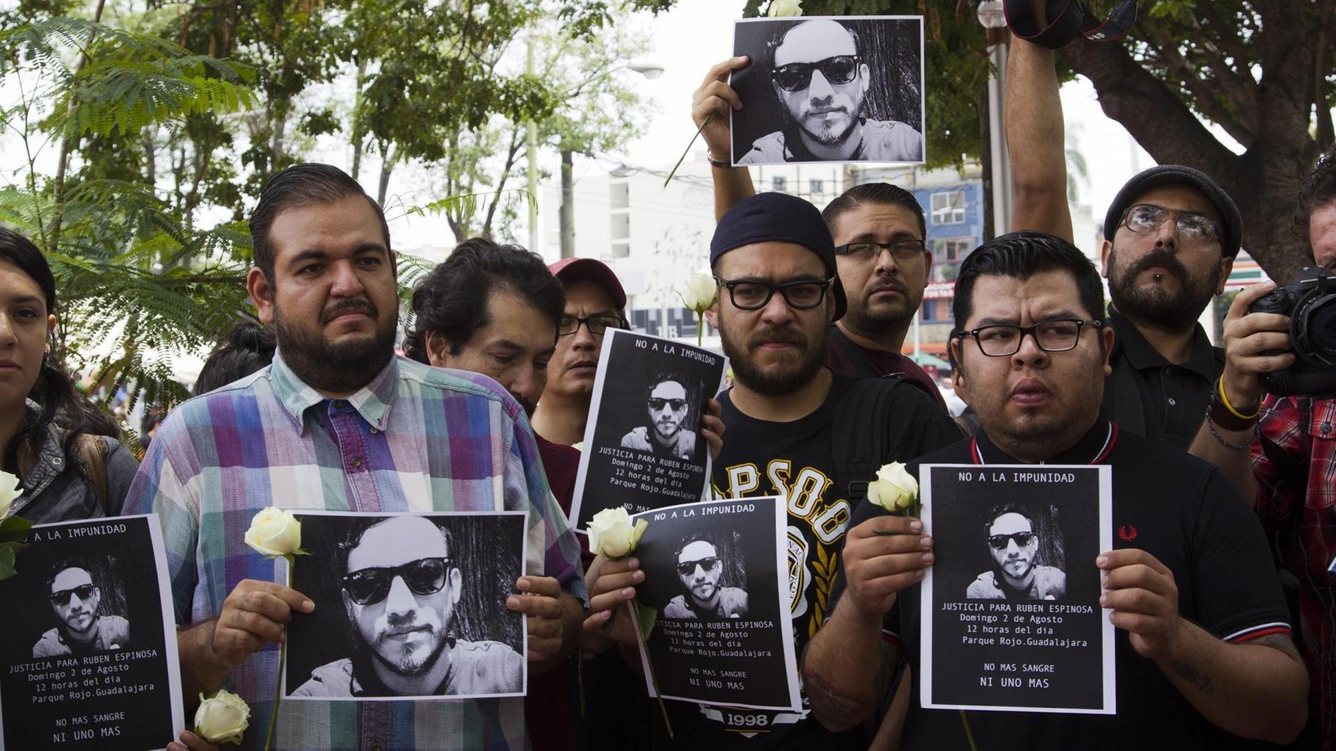 Mexikanische Journalisten halten Bilder ihres ermordeten Kollegen und weiße Blume als Zeichen der Trauer in den Händen.