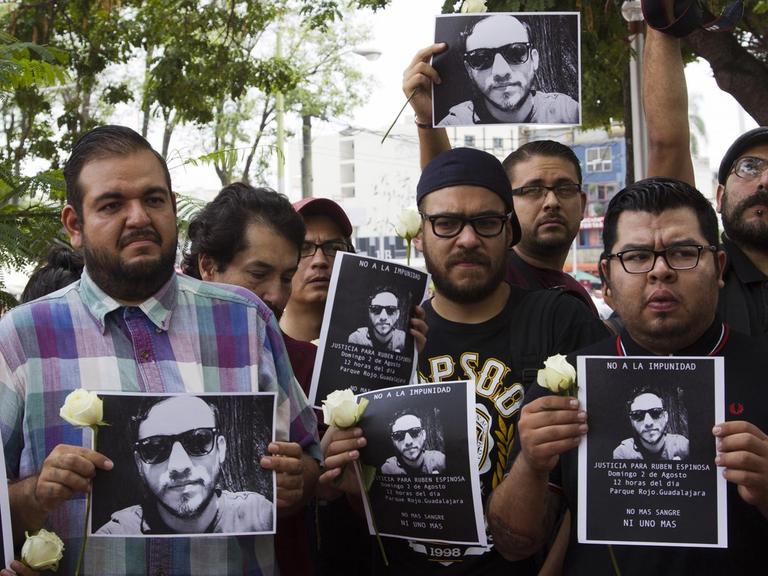 Mexikanische Journalisten halten Bilder ihres ermordeten Kollegen und weiße Blume als Zeichen der Trauer in den Händen.