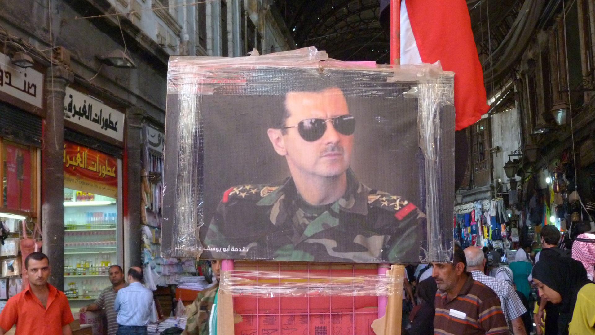 Auf dem Markt in Damaskus wird ein Gemälde verkauft, auf dem Assad portratiert ist.