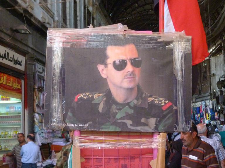 Auf dem Markt in Damaskus wird ein Gemälde verkauft, auf dem Assad portratiert ist.