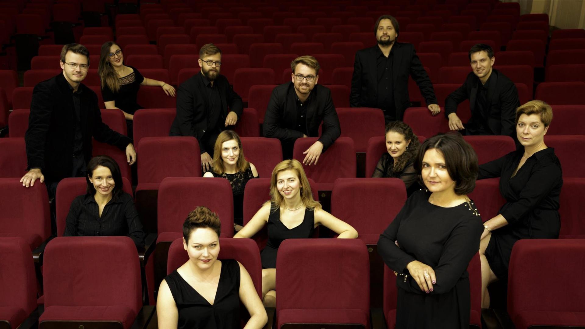 Die Mitglieder des Ensembles Cracow Singers sitzen in vertreut in einem Theatersaal auf roten Samtsesseln. Die Mitglieder des Ensembles Cracow Singers sitzen in vertreut in einem Theatersaal auf roten Samtsesseln.