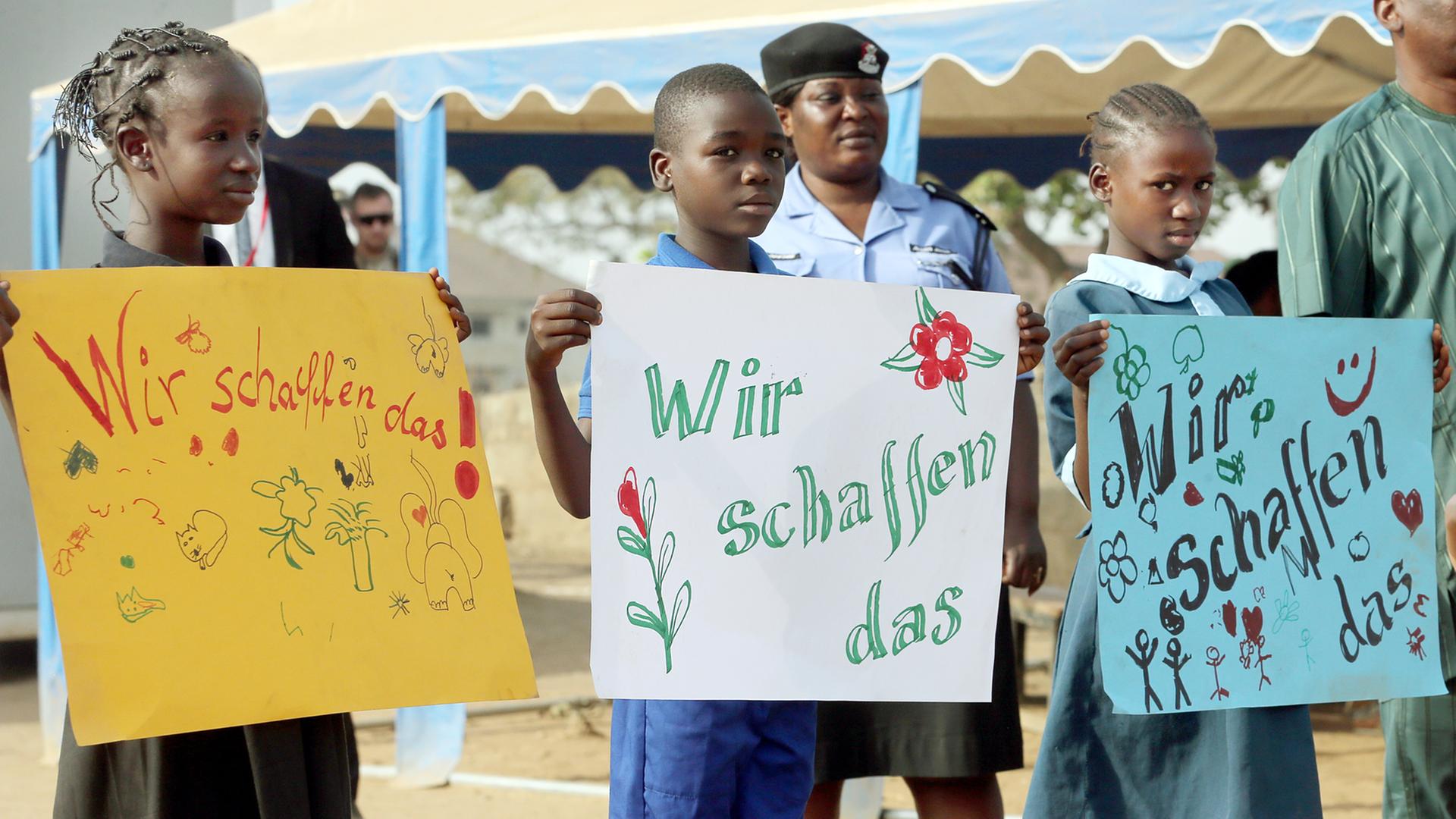 Kinder halten in Abuja in Nigeria, im Lager für Binnenflüchtlinge New Kuchigoro, selbst gemalte Schilder mit der Aufschrift "Wir schaffen das" hoch, bevor der Bundespräsident kommt. Kinder halten in Abuja in Nigeria, im Lager für Binnenflüchtlinge New Kuchigoro, selbst gemalte Schilder mit der Aufschrift "Wir schaffen das" hoch, bevor der Bundespräsident kommt.