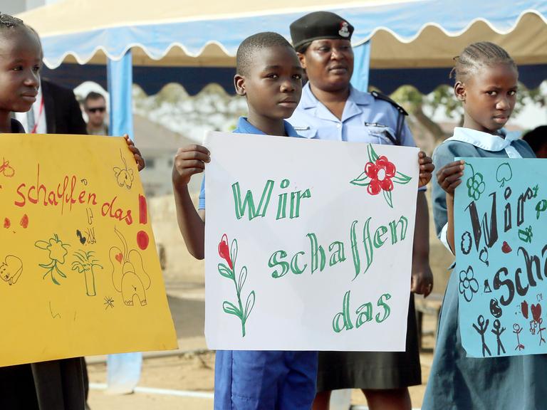 Kinder halten in Abuja in Nigeria, im Lager für Binnenflüchtlinge New Kuchigoro, selbst gemalte Schilder mit der Aufschrift "Wir schaffen das" hoch, bevor der Bundespräsident kommt.