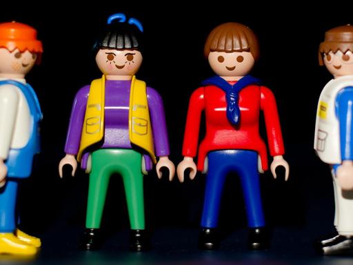 Zwei Playmobil-Frauen stehen zwischen zwei Playmobil-Männern