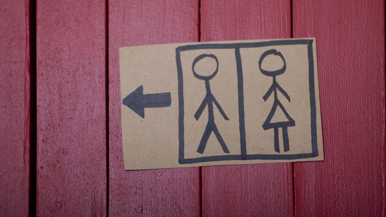 Das selbstgemalte Schild klebt an einer roten Wand aus Holzlatten. Das selbstgemalte Schild klebt an einer roten Wand aus Holzlatten.