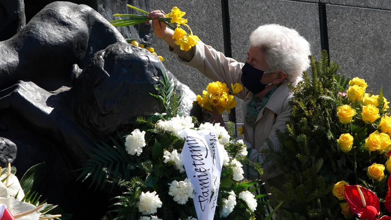 77. Jahrestag des Aufstands im Warschauer Ghetto: Eine ältere Frau mit Mundschutz legt Blumen nieder.