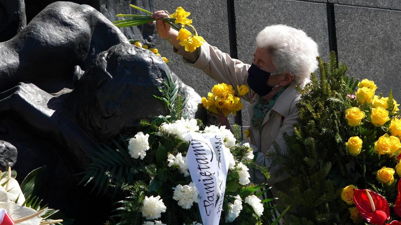 77. Jahrestag des Aufstands im Warschauer Ghetto: Eine ältere Frau mit Mundschutz legt Blumen nieder. 77. Jahrestag des Aufstands im Warschauer Ghetto: Eine ältere Frau mit Mundschutz legt Blumen nieder.