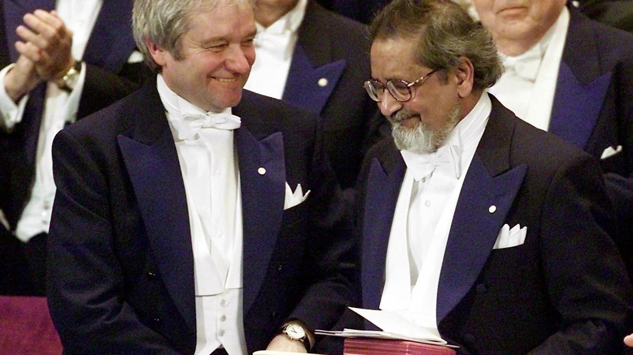 Der in Trinidad geborene britische Schriftsteller V.S. Naipaul (r) nimmt am 10. Dezember 2001 in Stockholm die Glückwünsche von Medizin-Nobelpreisträger Paul Nurse (l) entgegen, nachdem er mit dem Literatur-Nobelpreisausgezeichnet worden ist.