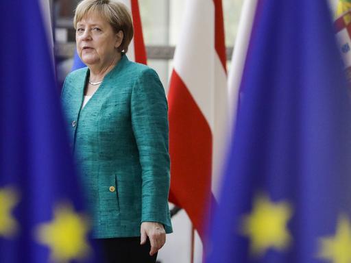 Bundeskanzlerin Angela Merkel läuft zwischen EU-Fahnen auf einem EU-Gipfel am 28. Juni 2018.