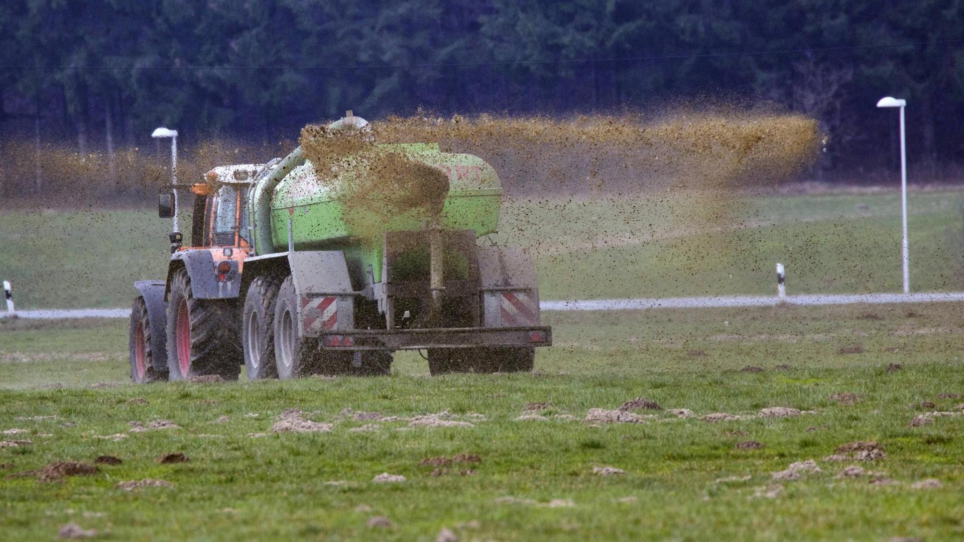 Ein Landwirt bringt mit seinem Trecker Gülle auf einem Feld aus. Ein Landwirt bringt mit seinem Trecker Gülle auf einem Feld aus.