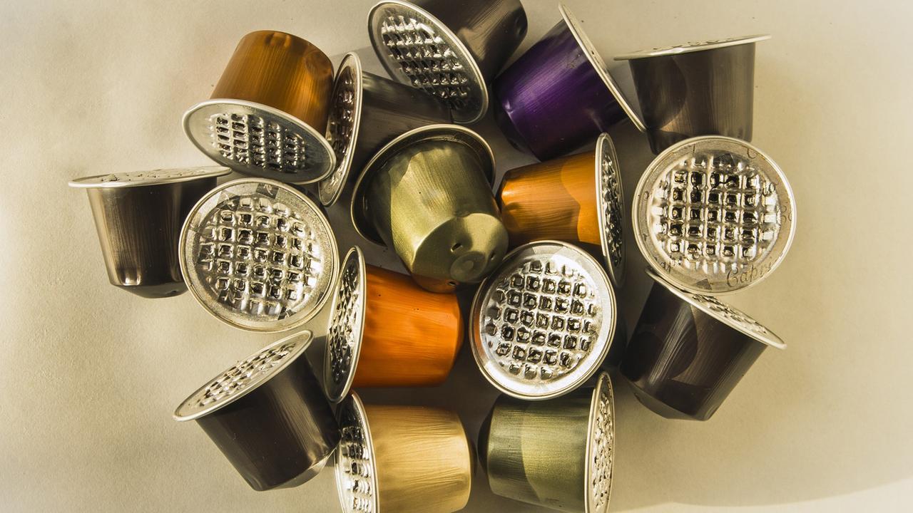 Einweg-Kapseln für Kaffee aus Aluminium liegen auf einem Tisch. Einweg-Kapseln für Kaffee aus Aluminium liegen auf einem Tisch.