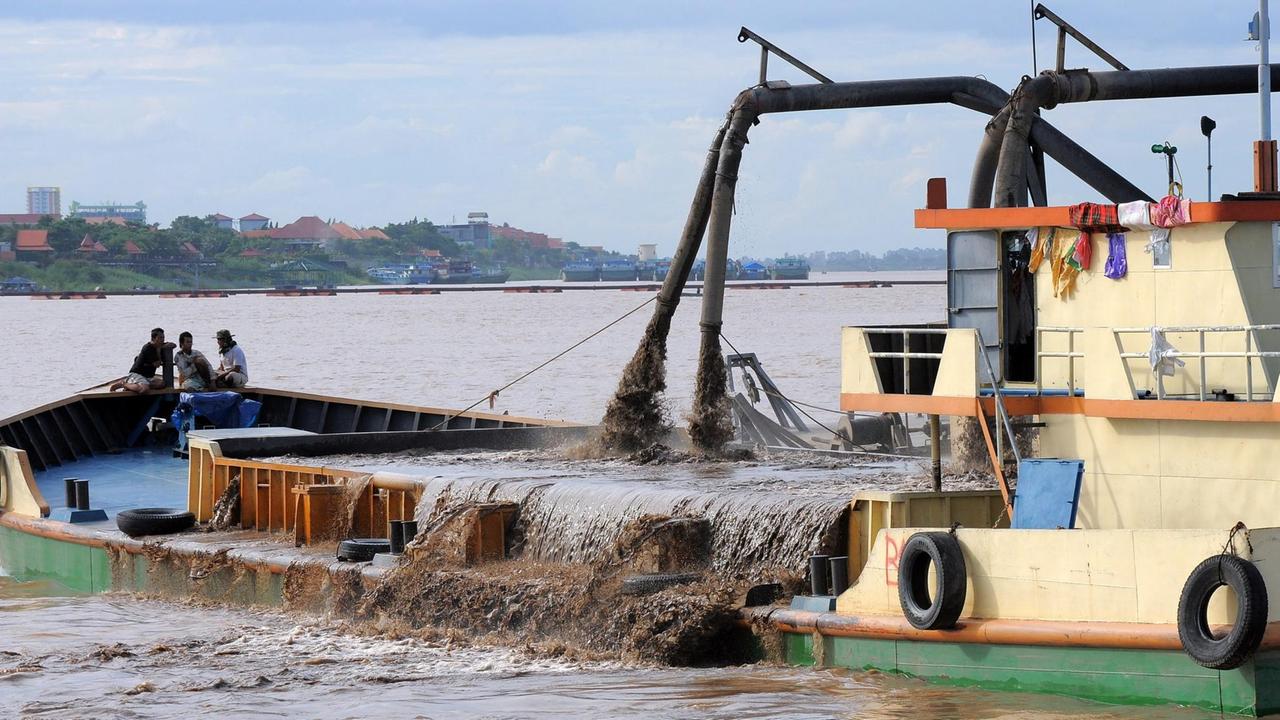 Ein Boot auf dem Mekong pumpt Sand ab und füllt die Ladung auf das Deck.