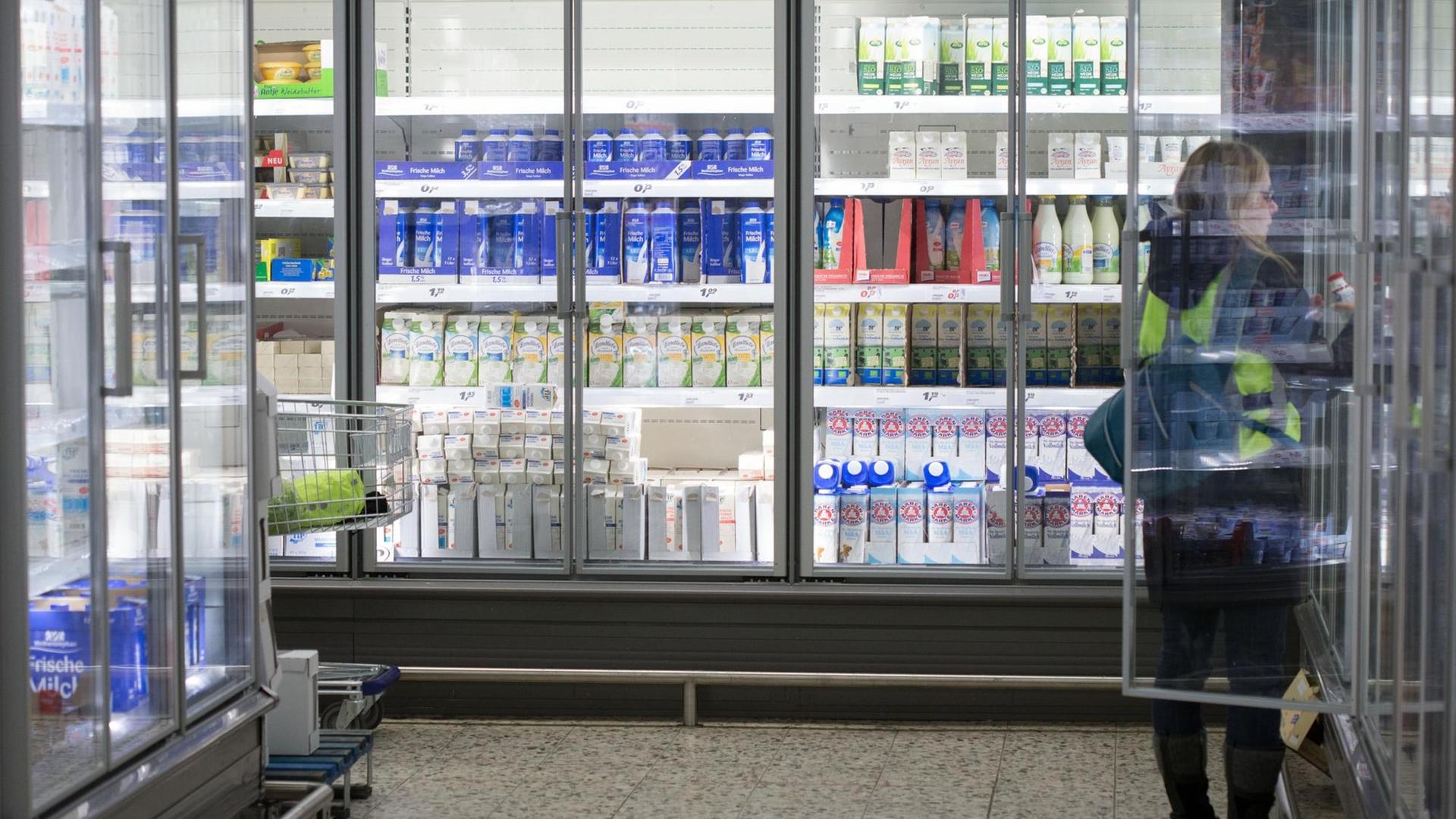 Eine Frau steht in einem Einkaufsmarkt vor einem Kühlregal mit Milchprodukten. Eine Frau steht in einem Einkaufsmarkt vor einem Kühlregal mit Milchprodukten.
