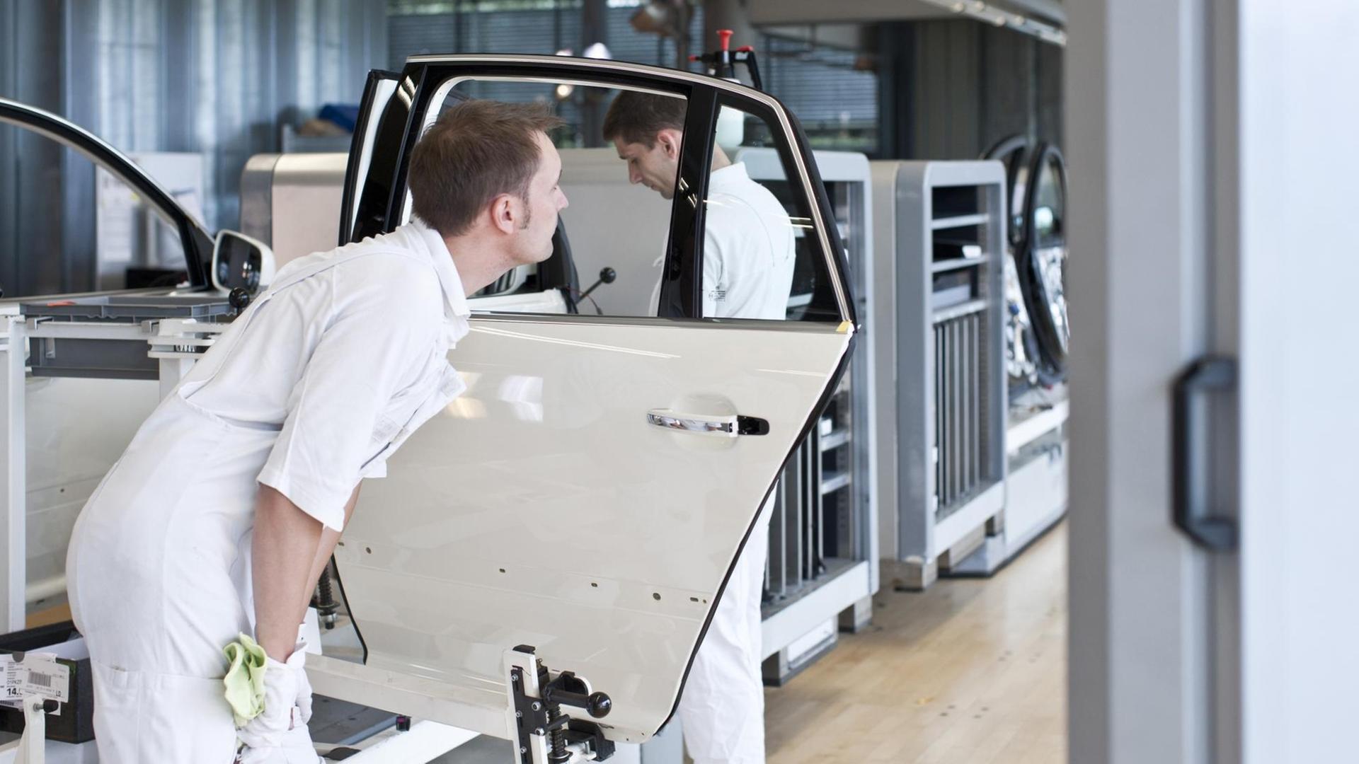 Ein Mitarbeiter prüft Glasscheiben in einer Tür für ein Auto. Ein Mitarbeiter prüft Glasscheiben in einer Tür für ein Auto.