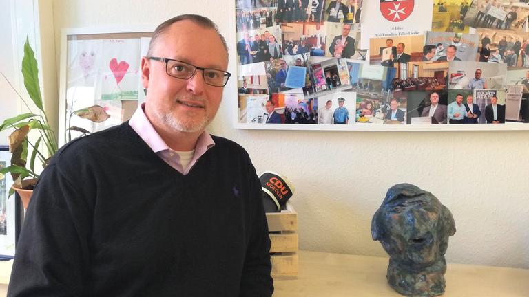 Ein Mann steht in einem Büro angelehnt an einen Schrank. Ein Mann steht in einem Büro angelehnt an einen Schrank.