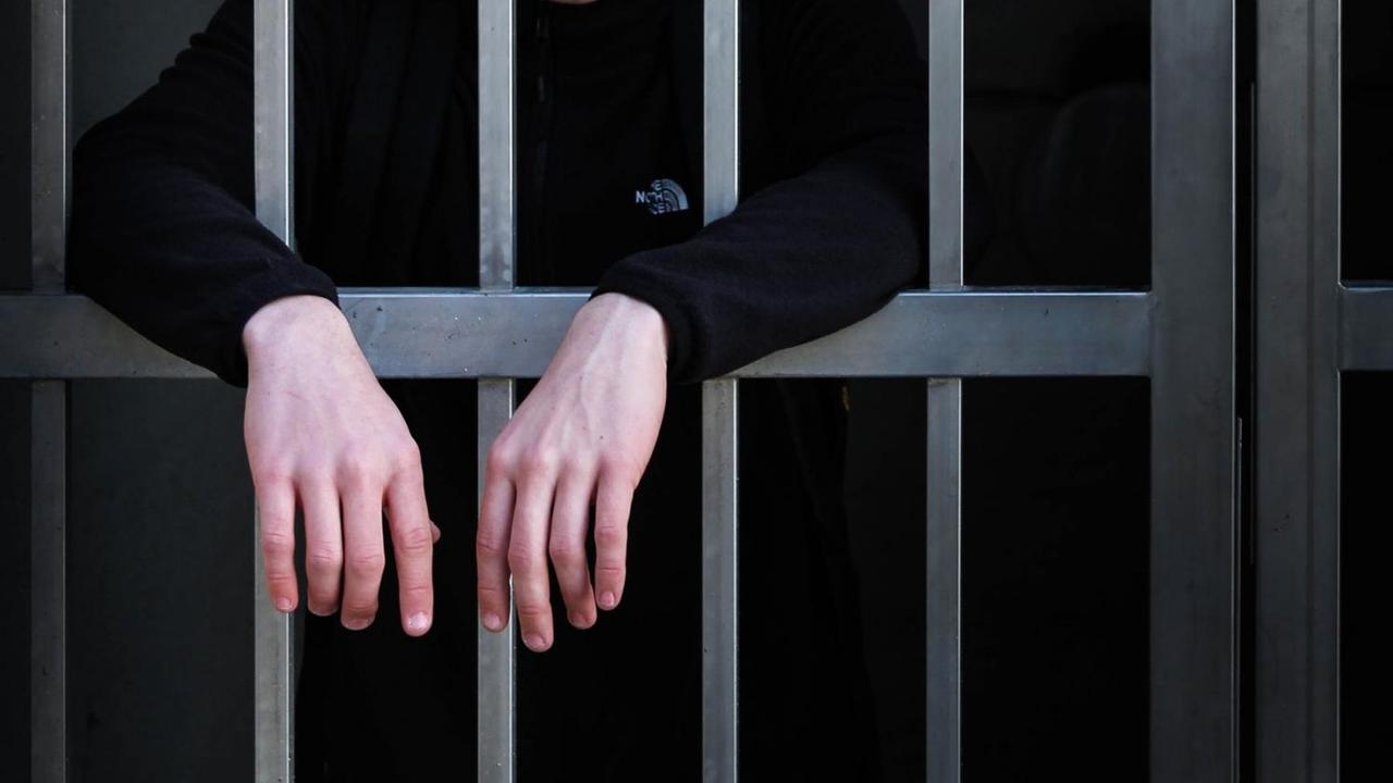 Hände an den Gittern einer Gefängnistür. Hände an den Gittern einer Gefängnistür.