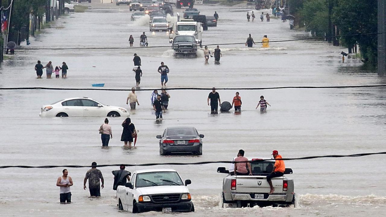 Passanten und Autos auf einer überfluteten Straße in Houston im US-Bundesstaat Texas am 27. August 2017. Passanten und Autos auf einer überfluteten Straße in Houston im US-Bundesstaat Texas am 27. August 2017.