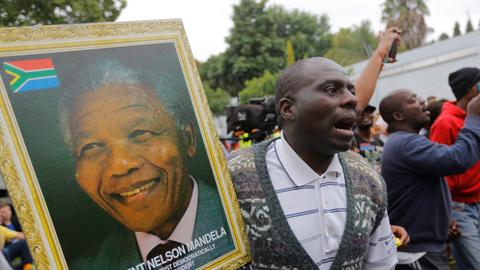 Ein Mann hält ein Portraitfoto des verstorbenen Nelson Mandela.