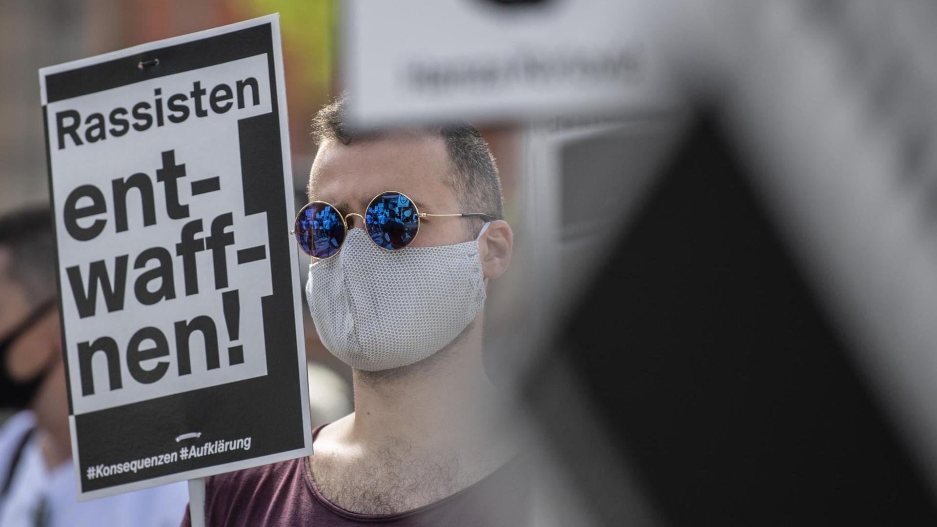 Ein Mann verfolgt eine Ansprache bei der offiziellen Gedenkveranstaltung zu den rassistisch motivierten Anschlägen in Hanau. Dabei hält er ein Schild mit der Aufschrift «Rassisten entwaffnen» in der Hand. Unter dem Motto «Erinnerung - Gerechtigkeit - Aufklärung - Konsequenzen» versammelten sich die Teilnehmer auf einem Platz in der Innenstadt. Aufgrund der aktuellen Corona-Infektionszahlen war die Teilnehmerzahl von der Behörden begrenzt worden. Ein Mann verfolgt eine Ansprache bei der offiziellen Gedenkveranstaltung zu den rassistisch motivierten Anschlägen in Hanau. Dabei hält er ein Schild mit der Aufschrift «Rassisten entwaffnen» in der Hand. Unter dem Motto «Erinnerung - Gerechtigkeit - Aufklärung - Konsequenzen» versammelten sich die Teilnehmer auf einem Platz in der Innenstadt. Aufgrund der aktuellen Corona-Infektionszahlen war die Teilnehmerzahl von der Behörden begrenzt worden.