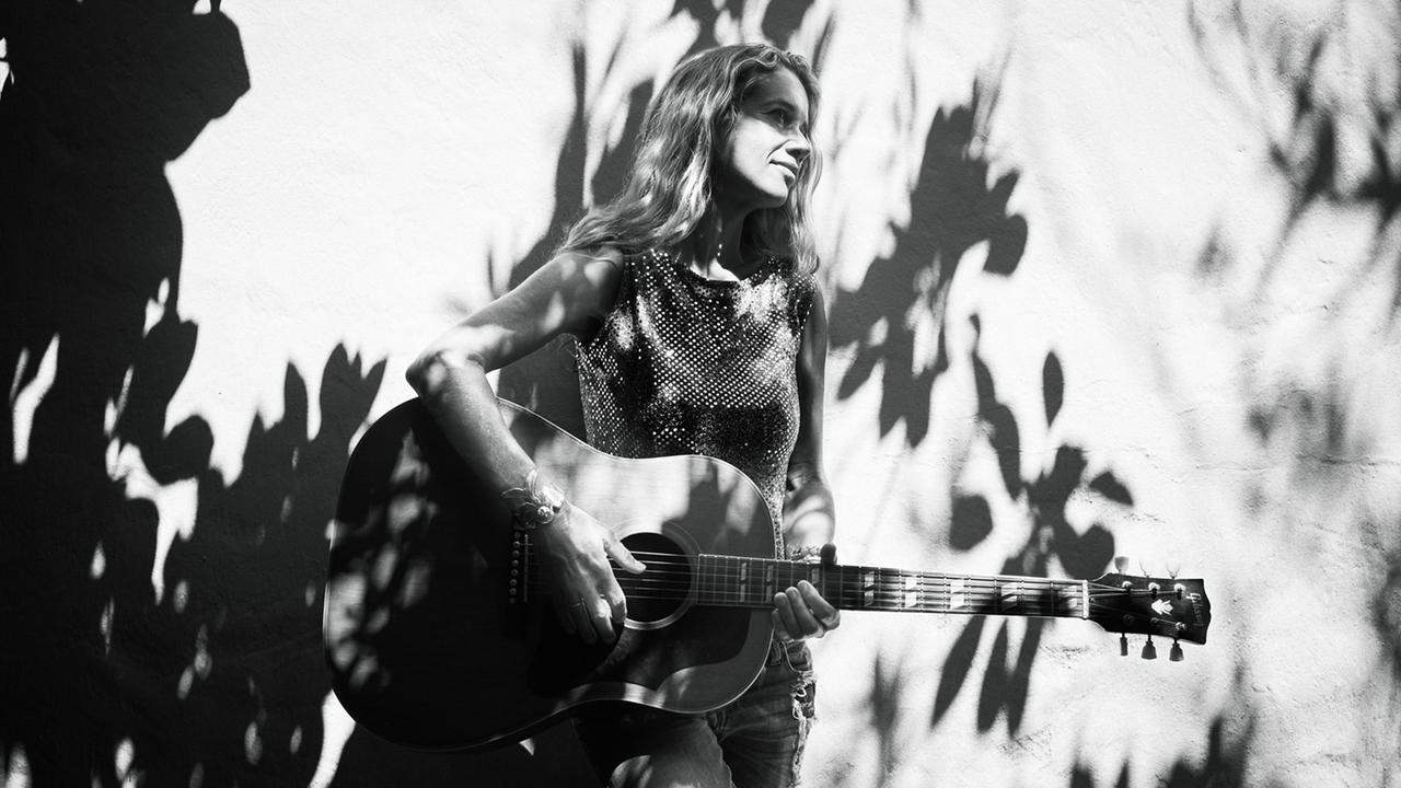 Heather Nova steht mit Gitarre an eine Wand gelehnt. Heather Nova steht mit Gitarre an eine Wand gelehnt.