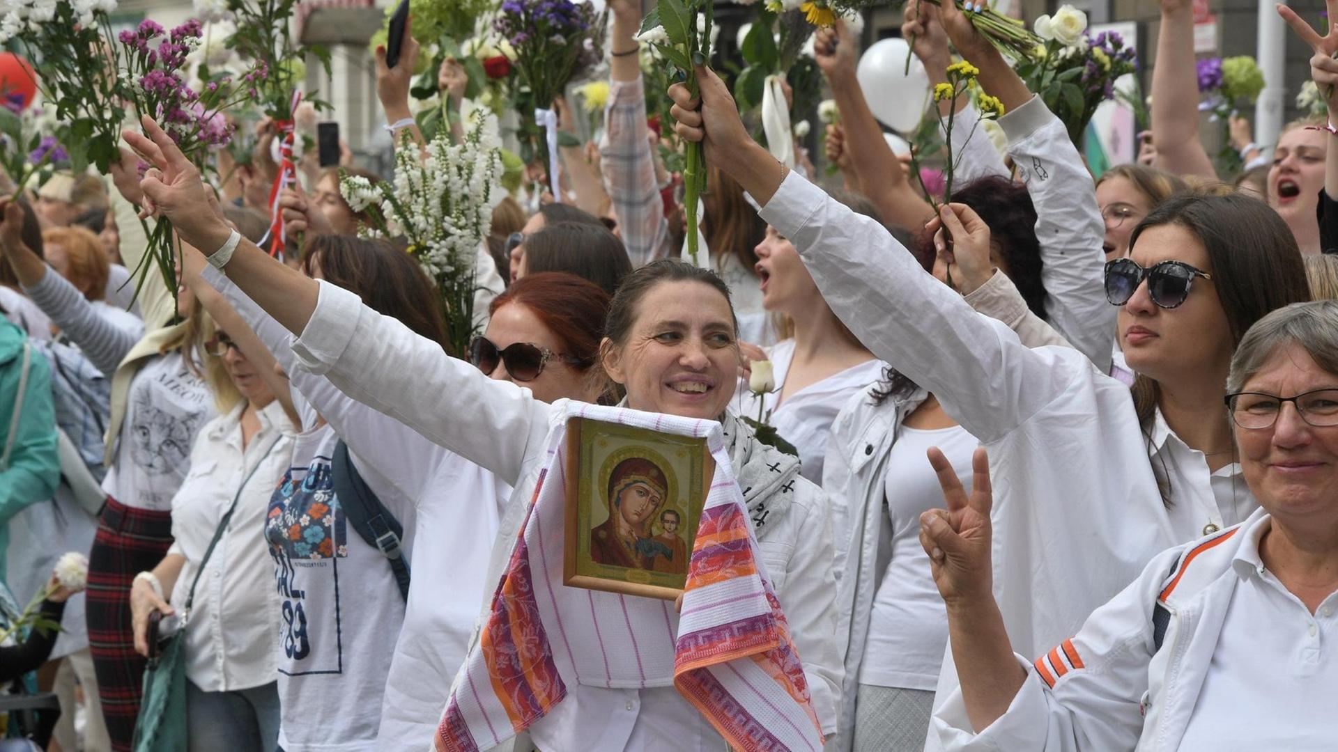 Frauen nehmen mit Blumen an den Demonstrationen gegen den Wahlbetrug bei den Präsidentschaftswahlen teil.