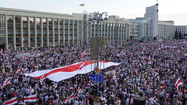 Sehr viele Menschen und eine große Flagge in rot und weiß bei einer Demonstration in Belarus