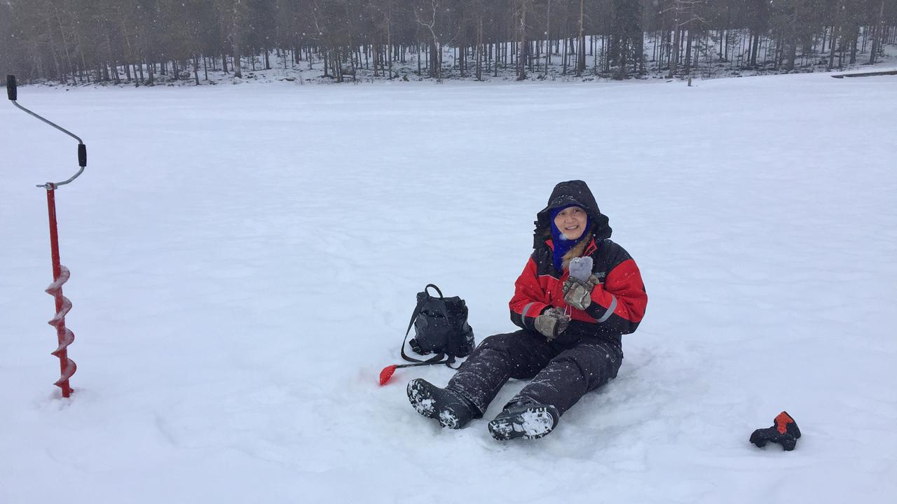 Ein asiatischer Tourist beim Eisfischen in Finnland. Ein asiatischer Tourist beim Eisfischen in Finnland.