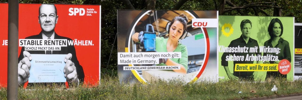 An einer Straße stehen große Wahl-Plakate von SPD, CDU und Grünen