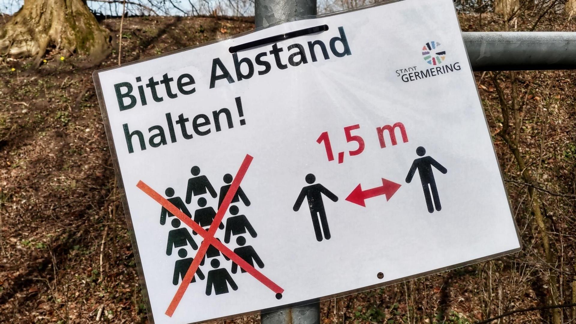 Auf einem an einem Laternenpfahl angebrachten Zettel steht: "Bitte Abstand halten". DIe Deutschen sind angewiesen in der Öffentlichkeit einen Mindestabstand von 1,5 Metern zueinander zu halten.
