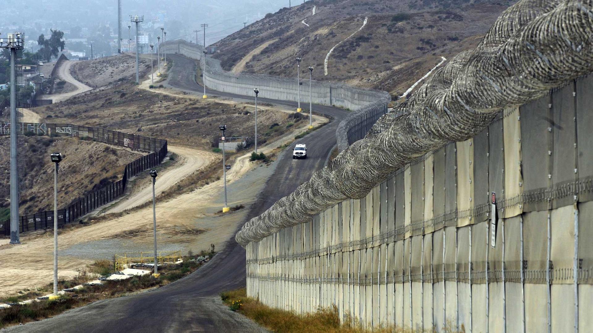 US-Grenzfahnder fahren in einem Auto an Mauern und Befestigungen an der Grenze zu Mexiko entlang, bei Otay Mesa, Kalifornien, USA, am 14. Oktober 2010. US-Grenzfahnder fahren in einem Auto an Mauern und Befestigungen an der Grenze zu Mexiko entlang, bei Otay Mesa, Kalifornien, USA, am 14. Oktober 2010.