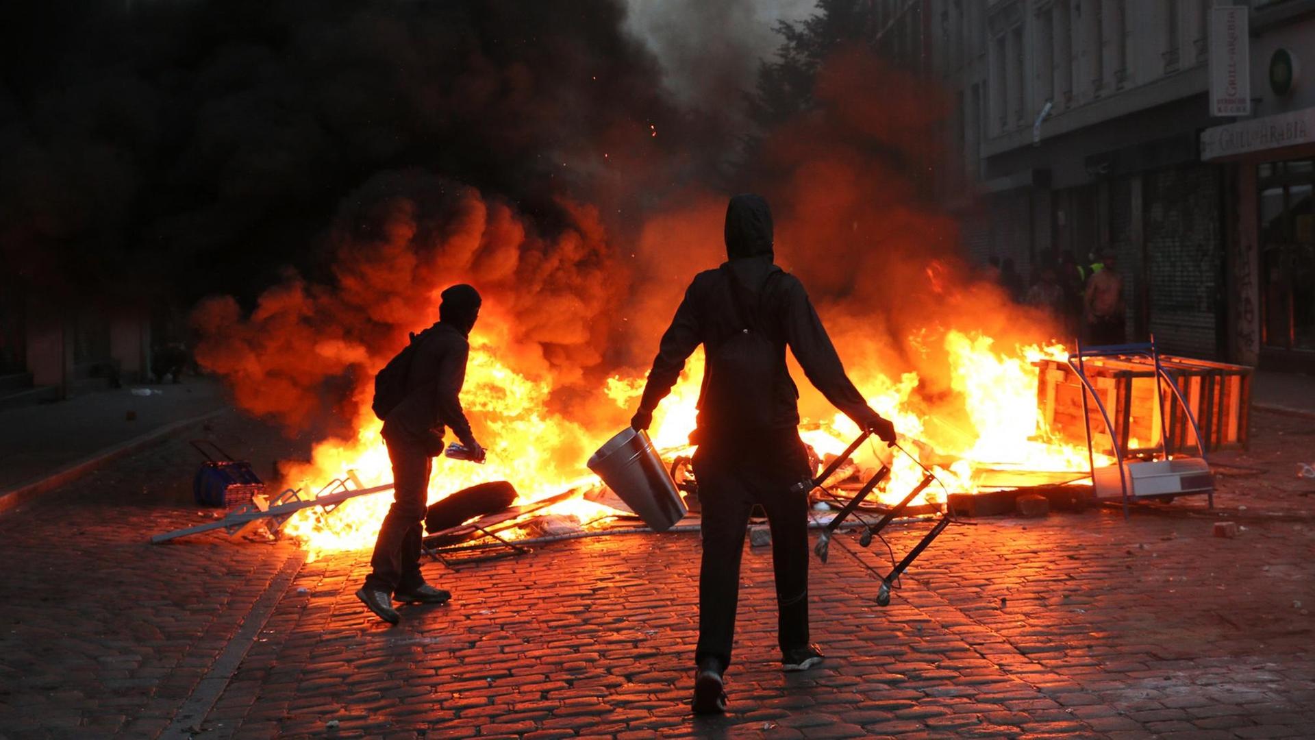 Randalierer stehen im Schanzenviertel in Hamburg vor einer brennenden Barrikade. file_source: Markus Scholz/dpa