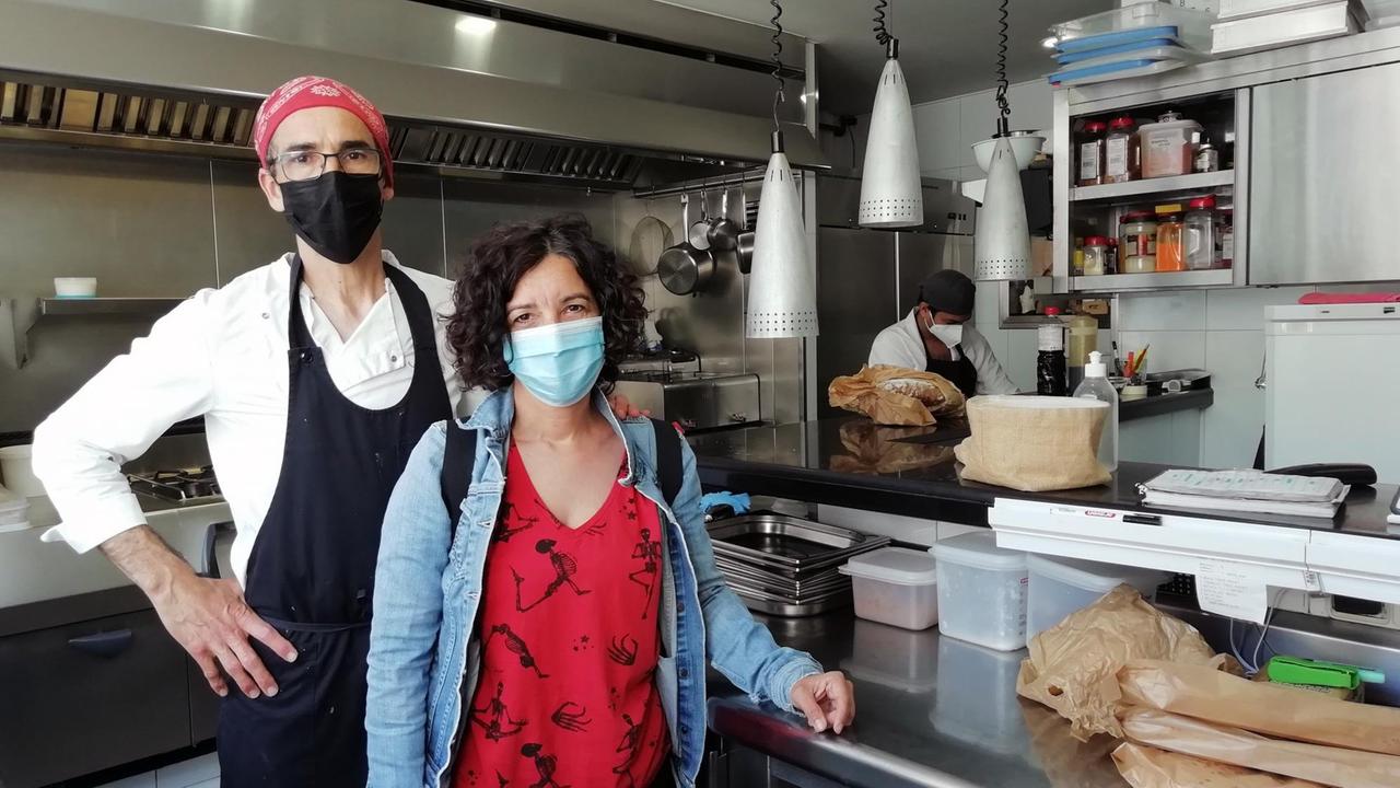 Maica und Juan Manuel Rubio stehen mit Mundschutz in der Restaurantküche. Maica und Juan Manuel Rubio stehen mit Mundschutz in der Restaurantküche.