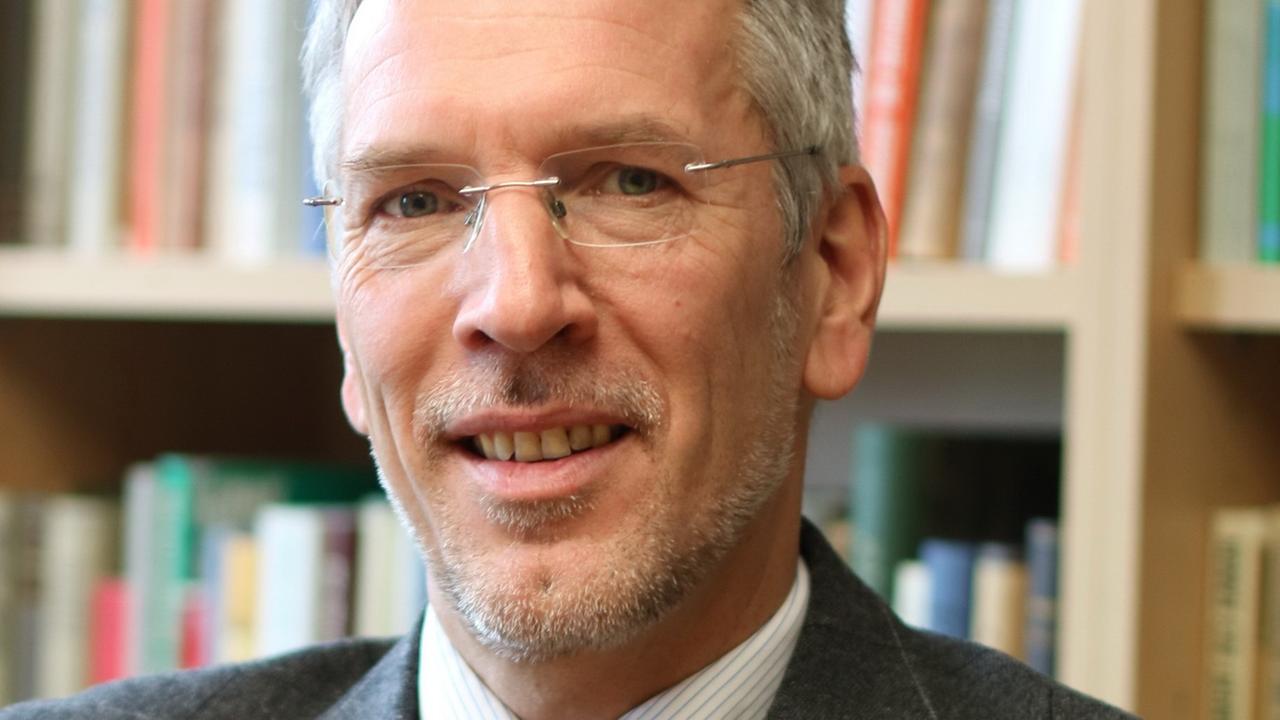 Ein bebrillter, grauhaariger Mann lächelt in die Kamera. Ein bebrillter, grauhaariger Mann lächelt in die Kamera.