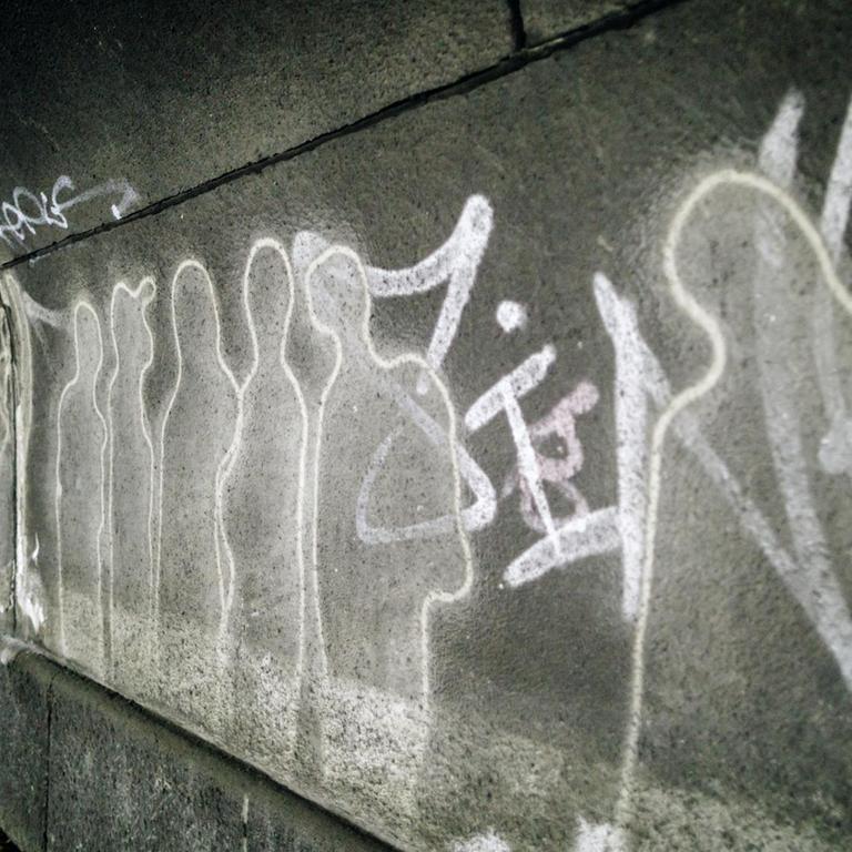 Auf dem Gelände des Loveparade-Unglücks erinnern Menschenumrisse an der Wand an die Vorfälle.