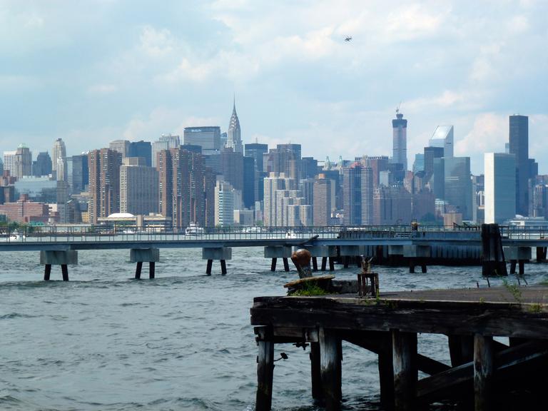Blick auf den East River mit Manhattan im Hintergrund, aufgenommen vom Ufer in Williamsburg, Brooklyn, New York am 22.06.2014